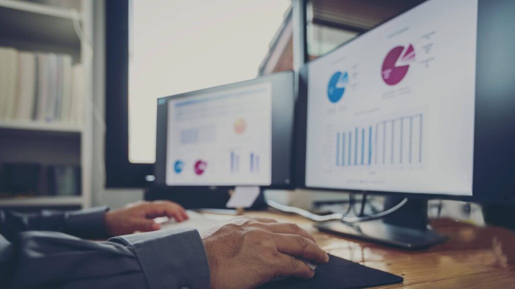 photo of two computer screens with various dashboards and optimisation processes