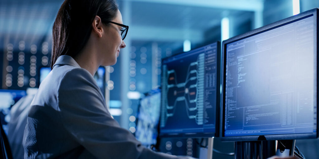 a woman programmer sitting at a desk in front of a computer looking at the screen with customer experience services