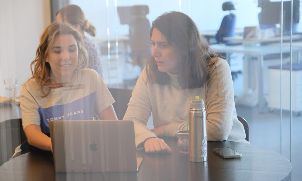 Two employees at the Spyrosoft office in Argentina sitting at a laptop.