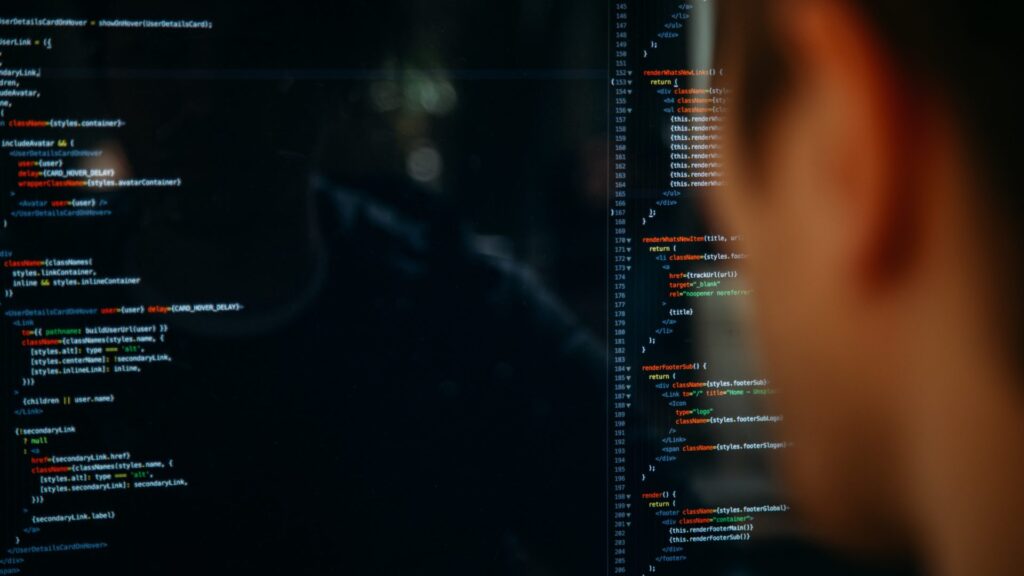 An over-the-shoulder view of a developer looking at lines of code on a dark-mode screen, representing the active software development of the 'Build' phase in a Build-Operate-Transfer (BOT) model.