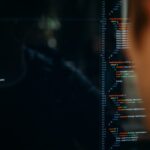 An over-the-shoulder view of a developer looking at lines of code on a dark-mode screen, representing the active software development of the 'Build' phase in a Build-Operate-Transfer (BOT) model.