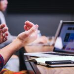 Team discussing project strategy during a meeting with laptop on the table – concept of build operate transfer model in software development