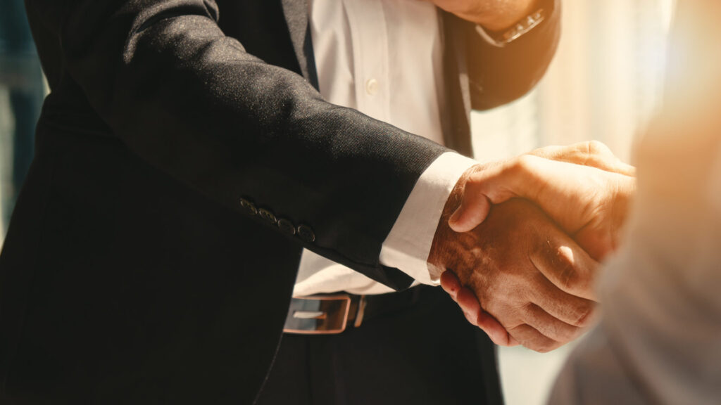 A close-up of a firm business handshake, symbolizing the trust and strategic partnership by efficient software development in the times of crisis