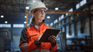 Industry 4.0 - IoT - IoT Development Services - woman at a factory reviewing data on her tablet