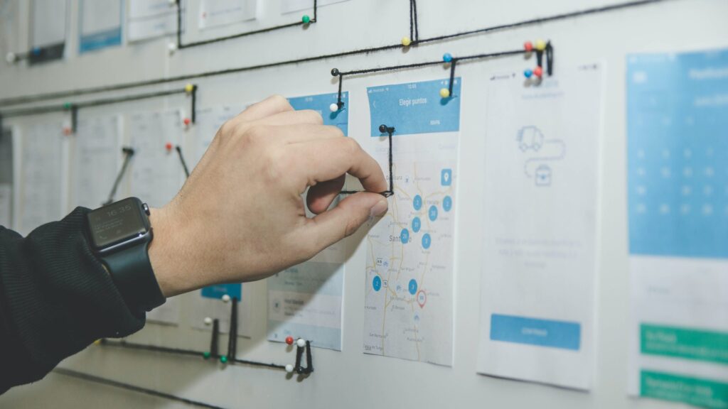 Hand pinning user journey maps and wireframes on a UX design board.