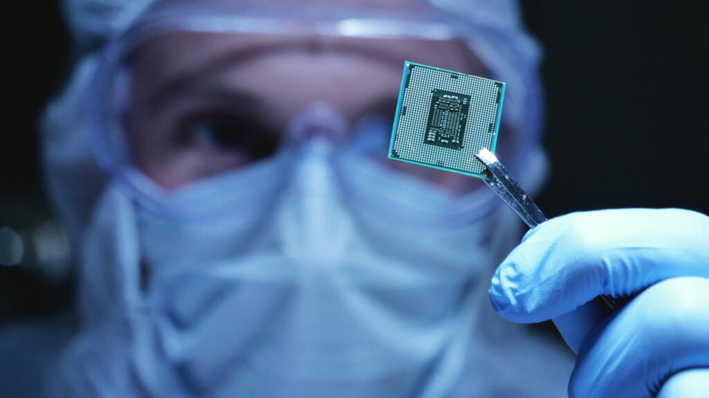 Technician in cleanroom holding a microchip processor with tweezers
