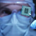 Technician in cleanroom holding a microchip processor with tweezers