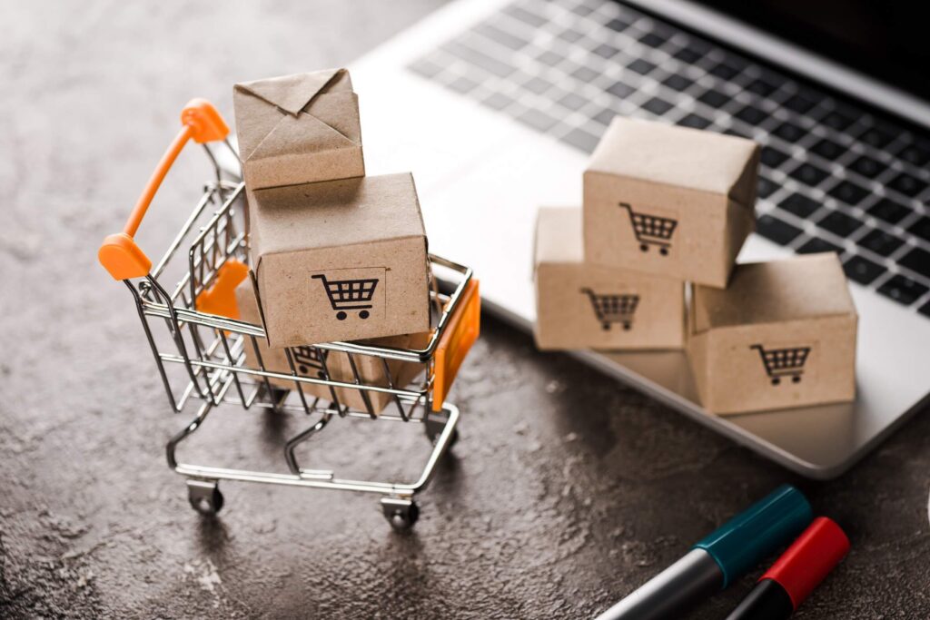 Mini shopping cart with cardboard boxes placed on a laptop keyboard – symbol of ecommerce growth and future online shopping trends