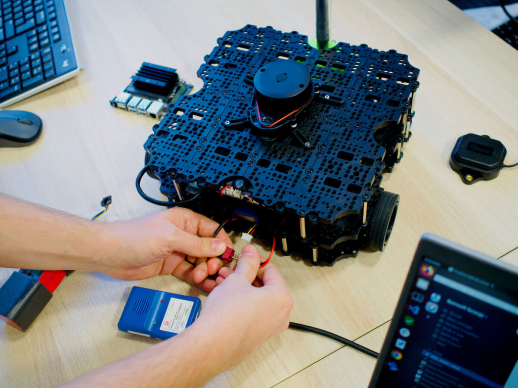 Hands working with wires of the Dojos' robotics project - a robot called Avatar.