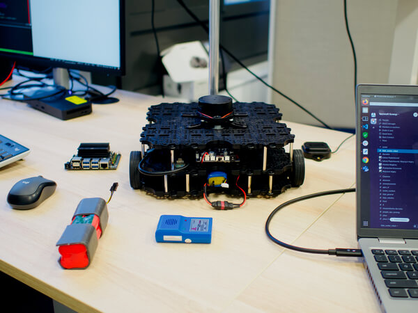 A robot called Avatar, an autonomous mobile robot that moves in indoor spaces, on the desk next to a laptop and tools.