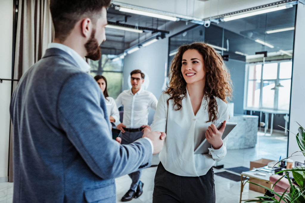 Customer churn prediction with Google AutoML; two people man and woman shaking hands in an office setting