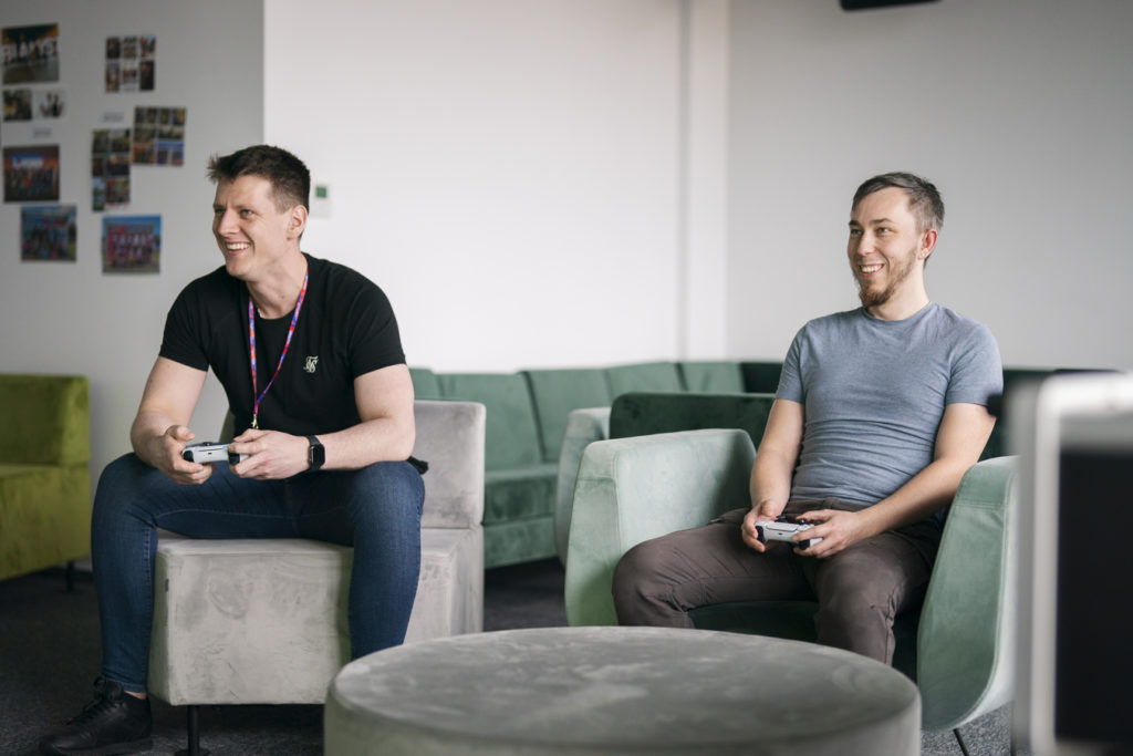 People in the Spyrosoft's Bialystok office smiling, laughing and playing video games on the PlayStation during their work break