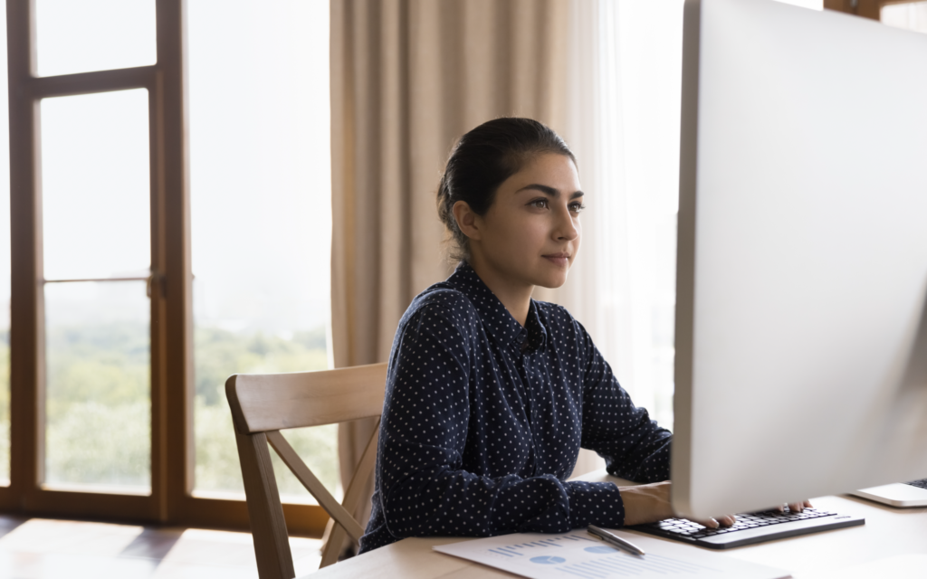 A woman in front of a desktop computer working on text analytics and nlp