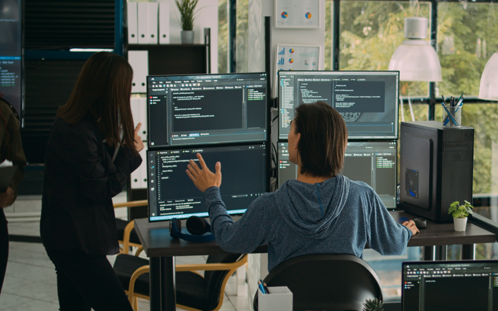 Two software developers in front of screens discussing text analytics and nlp