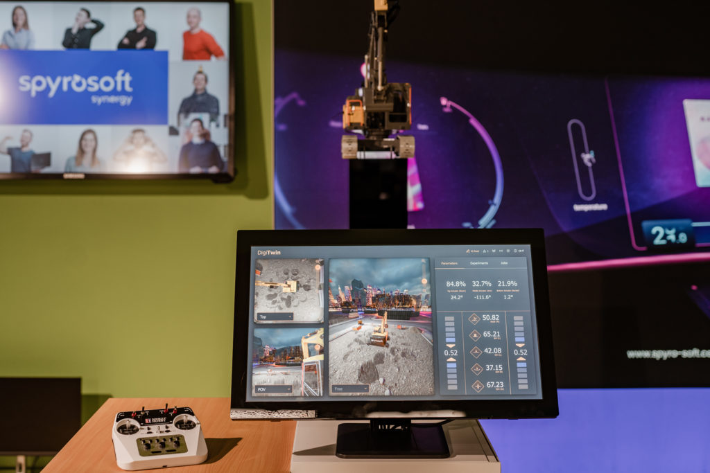 A digital twin of a mini excavator and a screen showing the excavator in 3D at the construction site.
