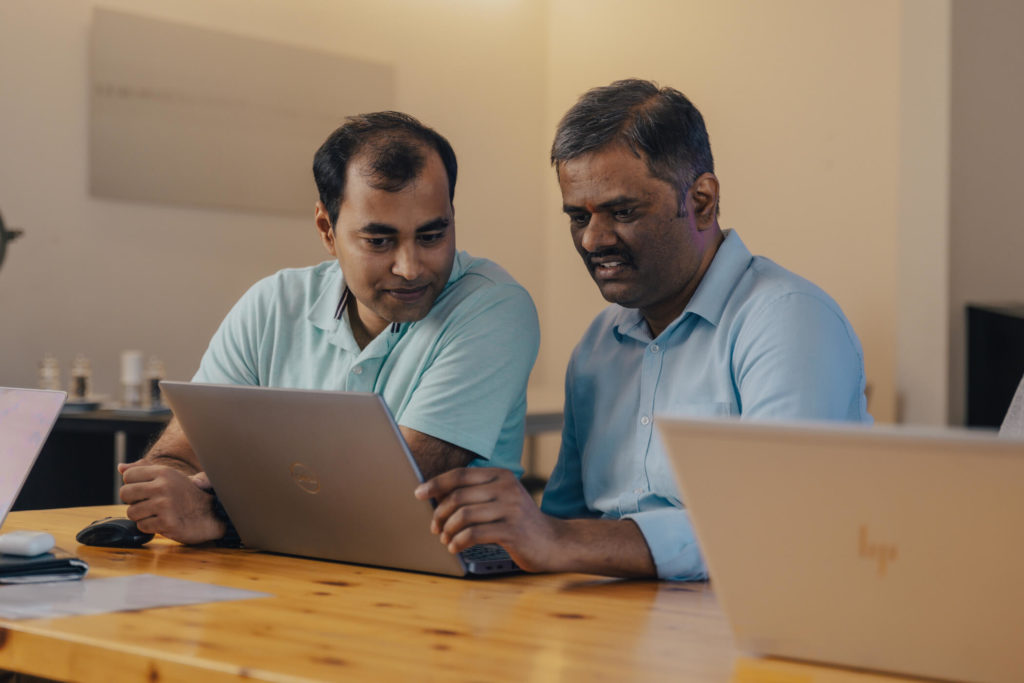 A pair of people are working on a laptop.