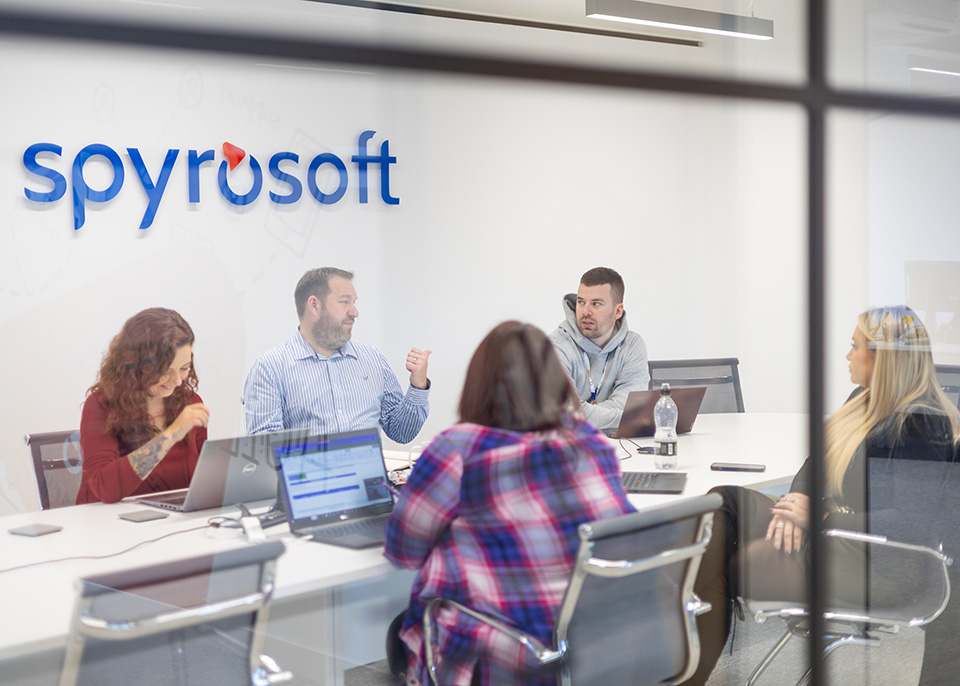 Team of people at work, brainstorming in a conference room, visible company logo, Spyrosoft Nordics and Spyrosoft UK.