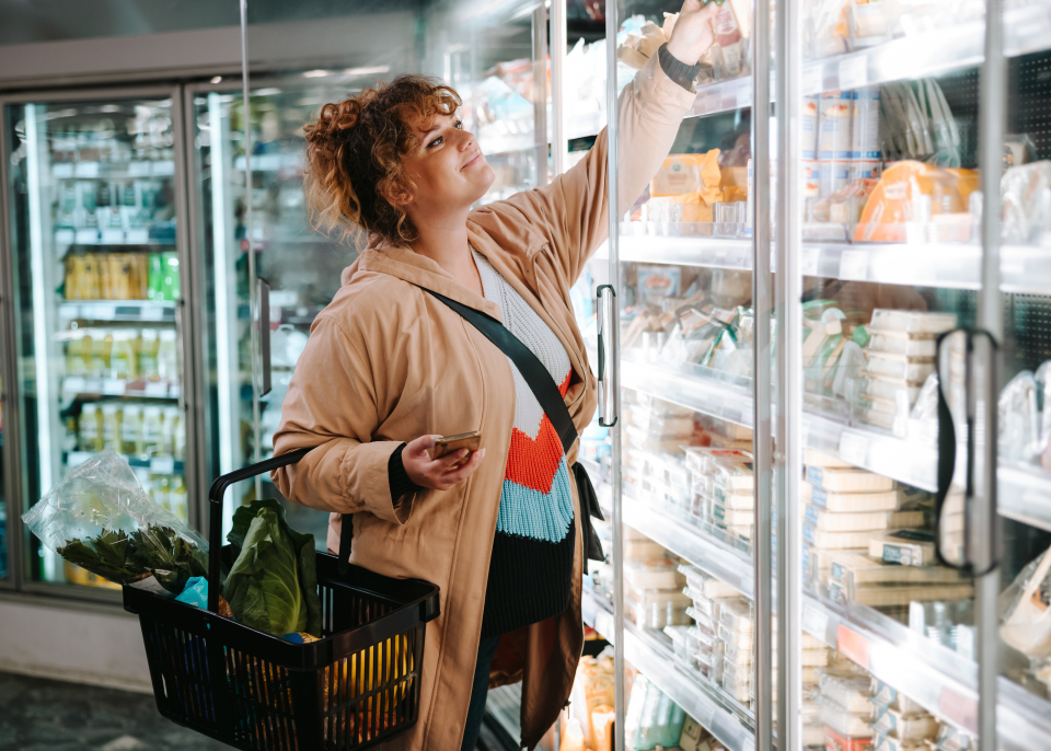 kobieta w sklepie spożywczym typu żabka sięgająca po produkty z lodówki