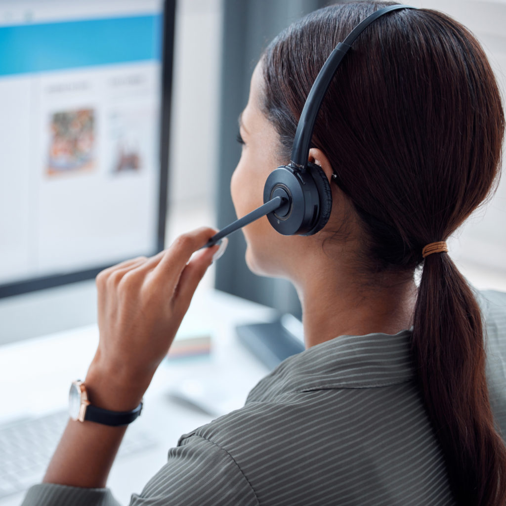 A business representative is talking via a headset, discussing CRM systems with a client.