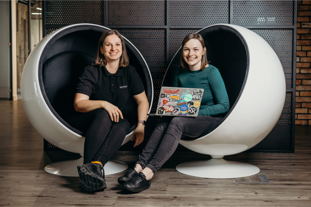 Two women are talking about Salesforce Commerce Cloud while sitting in big white chairs.