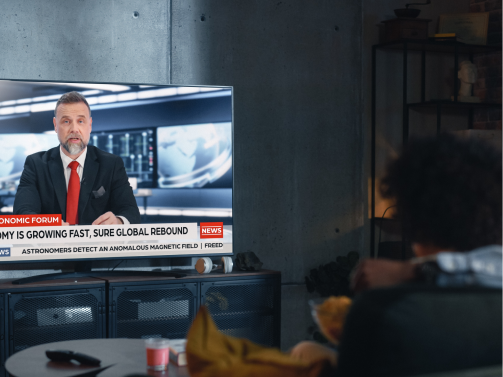Person watching news broadcast on TV – media and entertainment content distribution example
