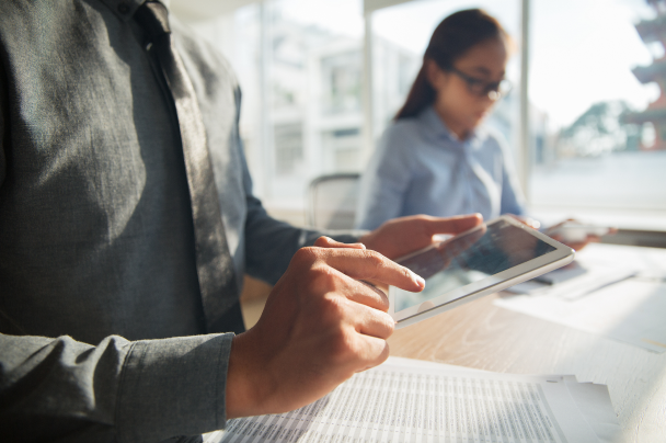 Business professionals analyzing data on a tablet and documents – broadcasters insights and OTT strategy planning