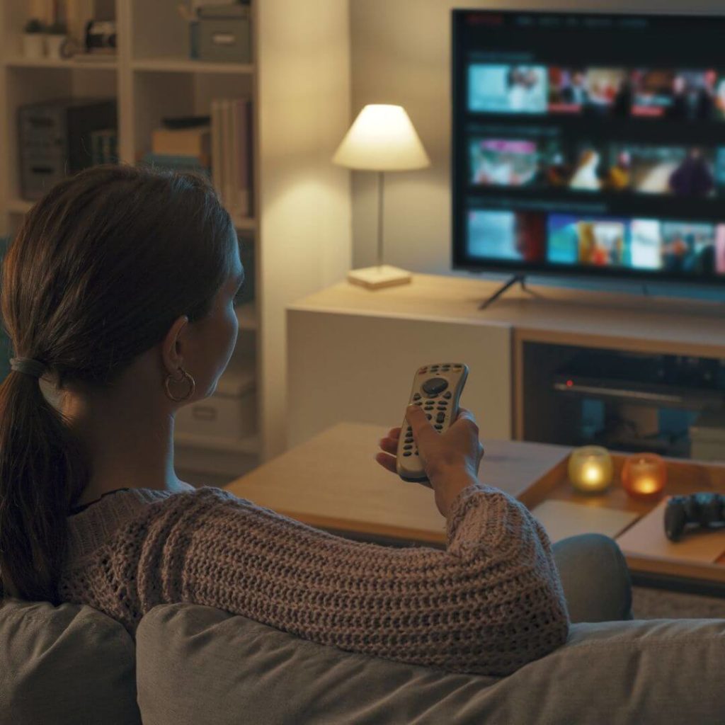 Woman browsing streaming platform on TV at home – OTT services and video-on-demand experience