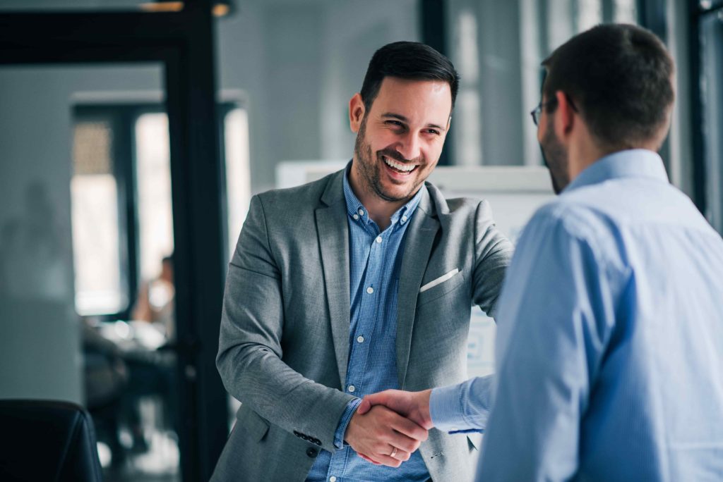 two men smiling and shaking hands in the office after streamlining cloud operations with AWS's Well-Architected