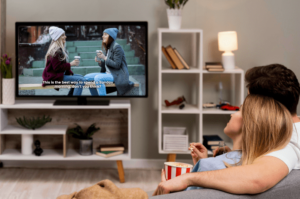 Event Organisers – couple sitting on a couch eating popcorn while watching a movie with subtitles on TV