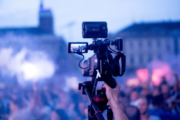 Event Organisers – camera operator filming a concert crowd at night