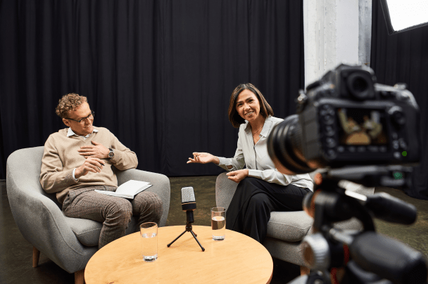 Telcos – man and woman recording interview or talk show in studio with camera and microphones