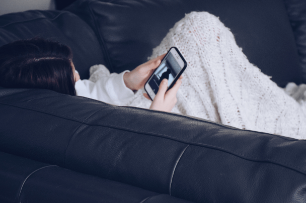 Event Organisers – woman lying on couch watching a video on smartphone