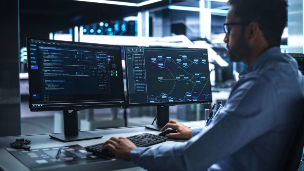 Person working on two screens, leveraging the BOT model to boost AI centre of excellence capabilities.