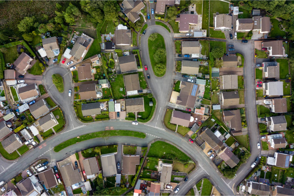Bird’s-eye view of a suburban residential area with curving roads and houses, representing land and property geospatial services.