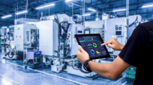 Person using a tablet to connect to factory equipment thanks to IoT protocols.