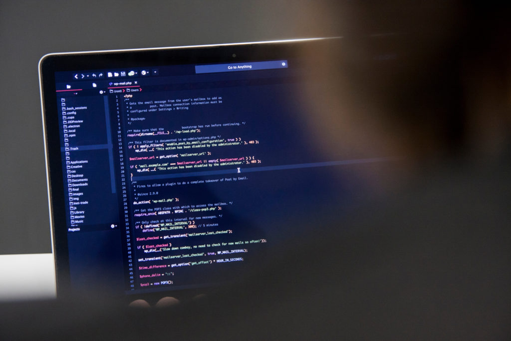male programmer working on laptop computer at white desk in office