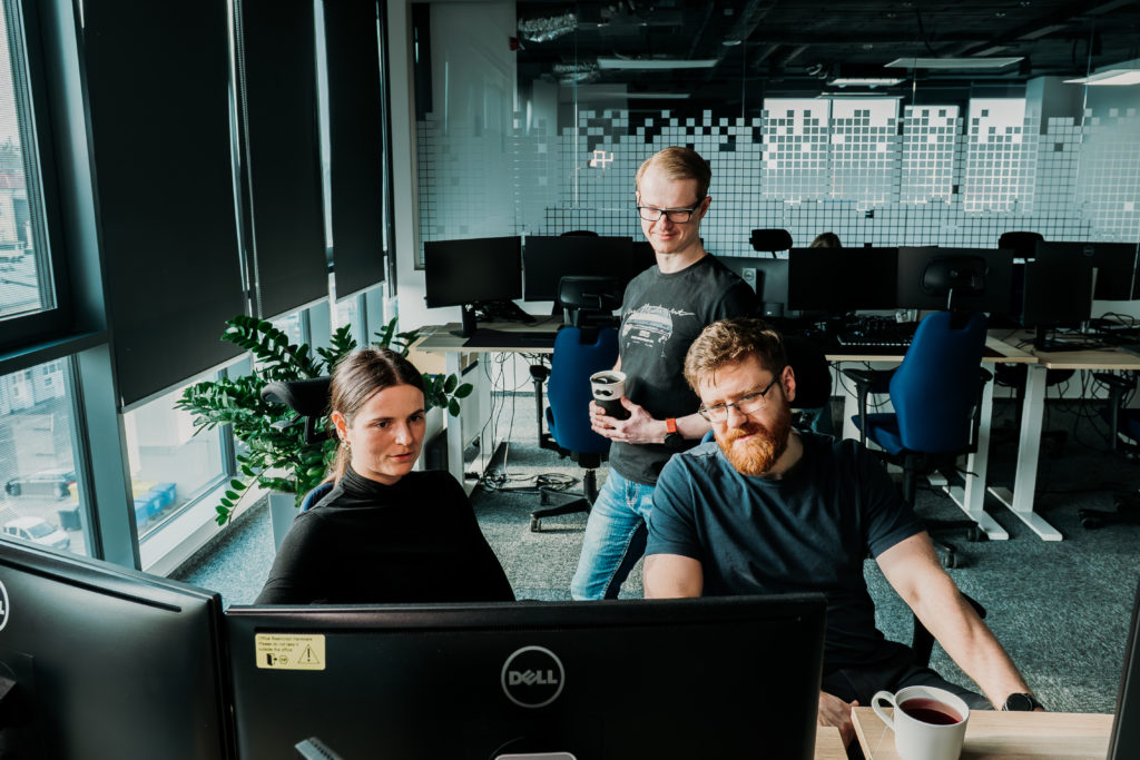 three software developers in front of a display, in an office