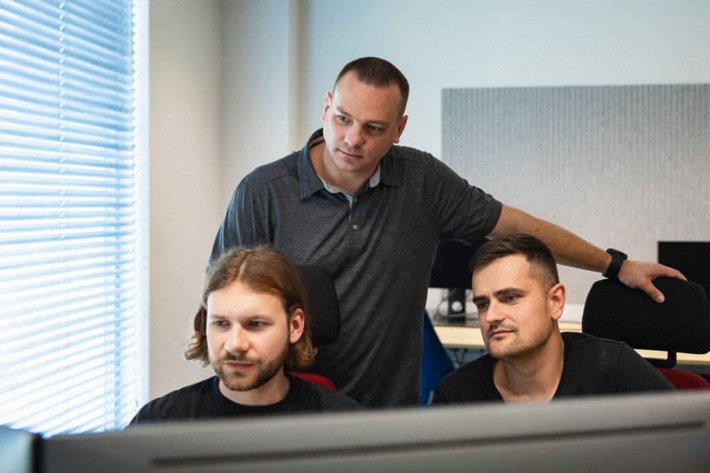 Team members of Spyrosoft AdTech looking at a computer- Spyrosoft AdTech technical consulting