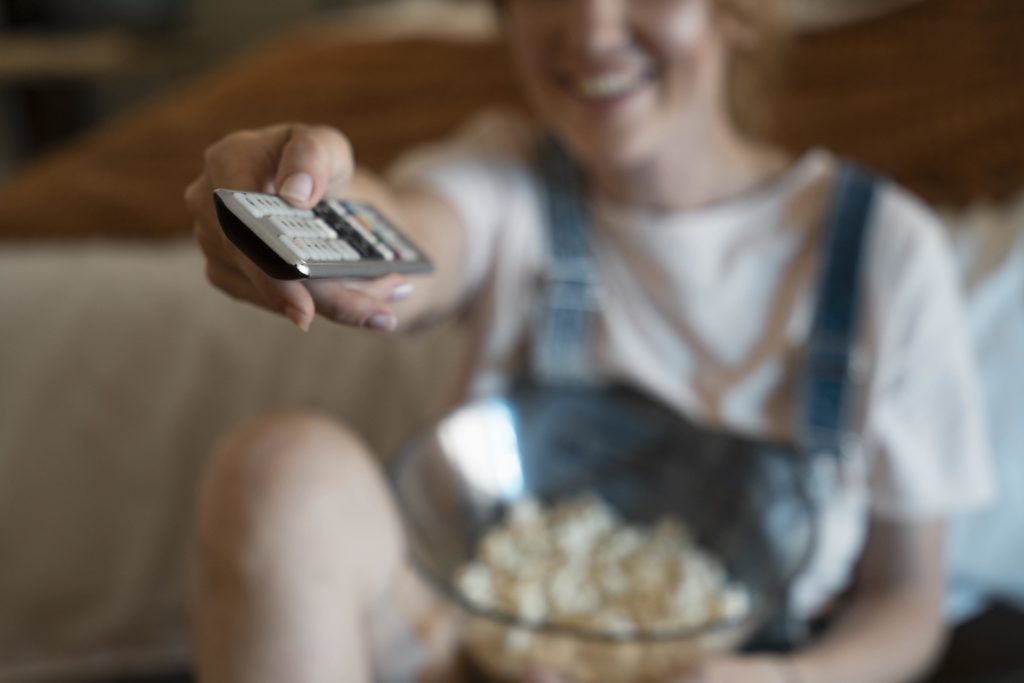 A woman sitting on couch browsing media and entertainment platforms