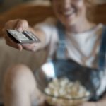 A woman sitting on couch browsing media and entertainment platforms
