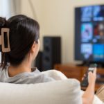 A woman sitting on a couch browsing media and entertainment platforms