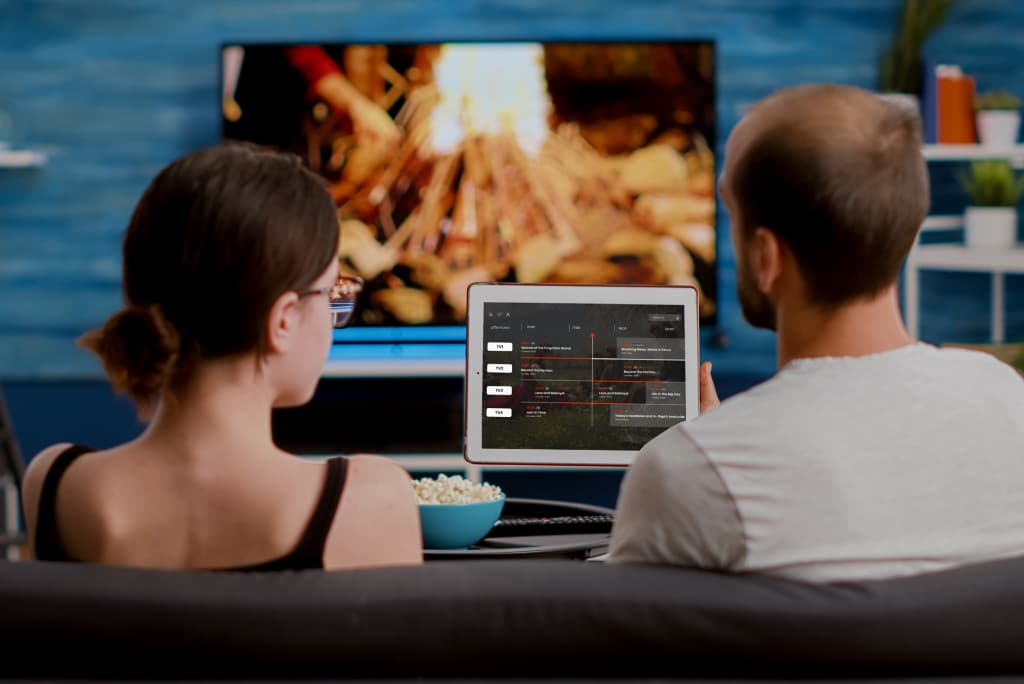 Couple using a tablet and TV for watching on-demand video – example of telcos offering OTT and streaming services across multiple devices