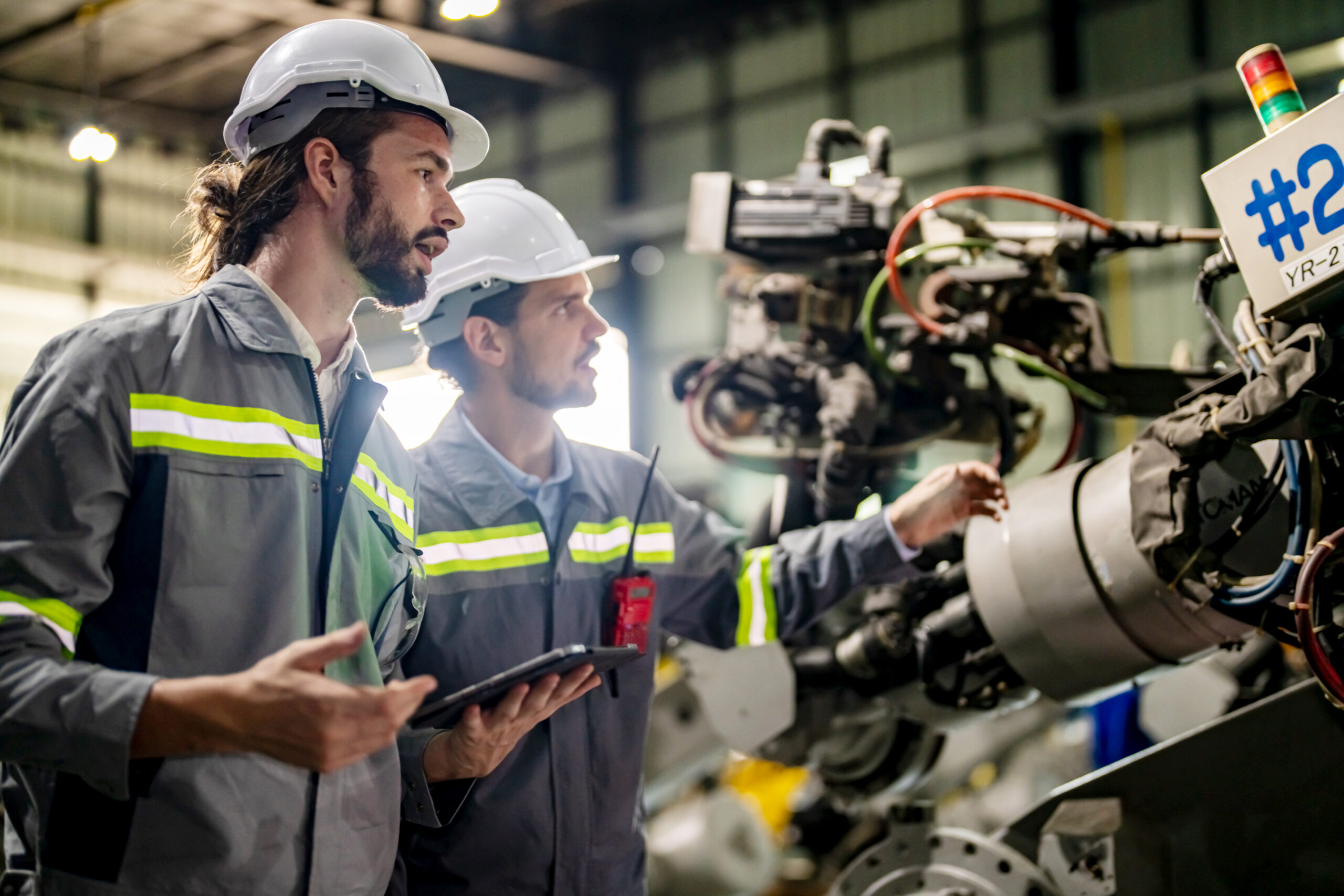 Engineer explaining to controlling robotic welding process to welder in Industry 4.0 factory.