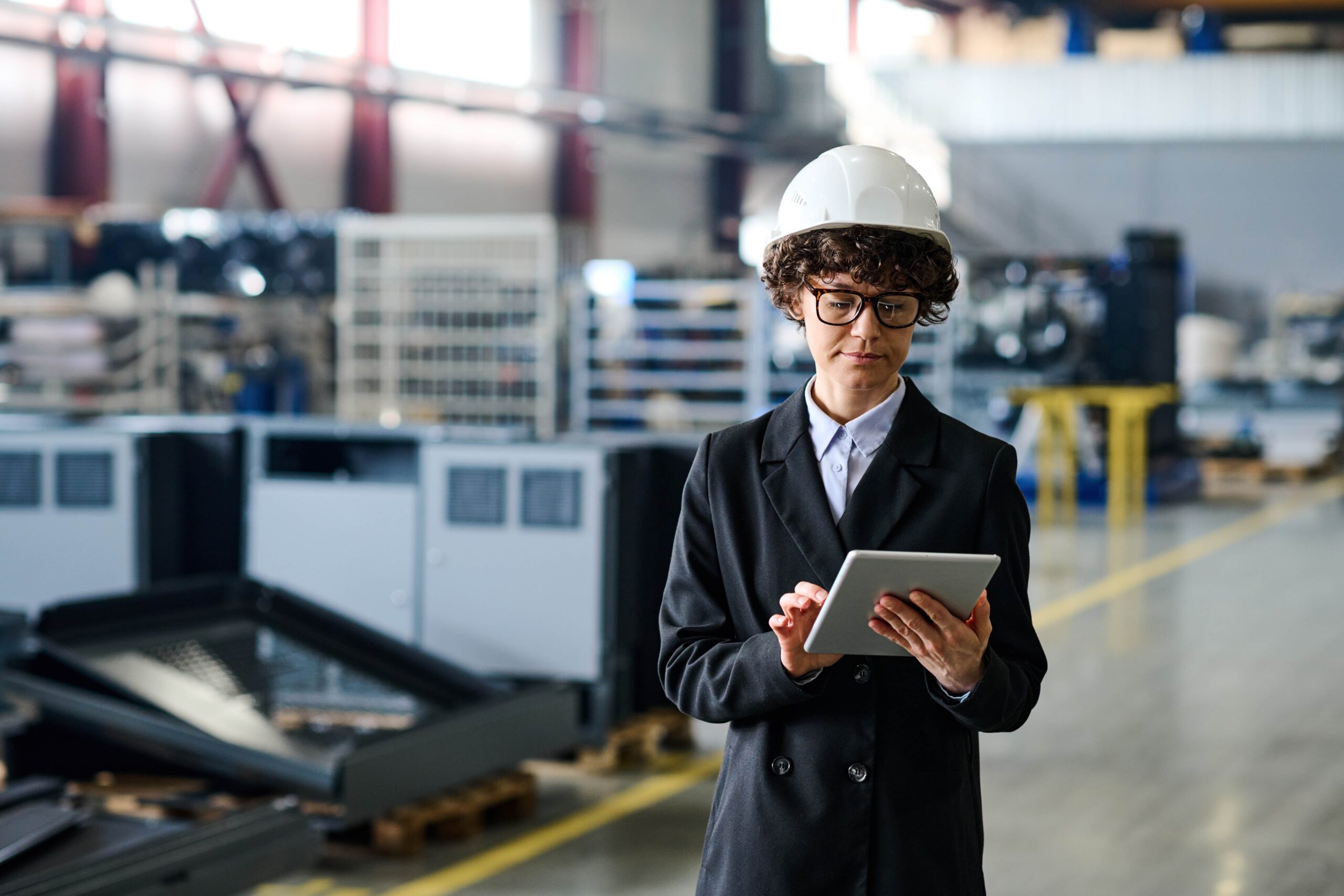 Female engineer looking through efficiency increase data while standing in an Industry 4.0 workshop.