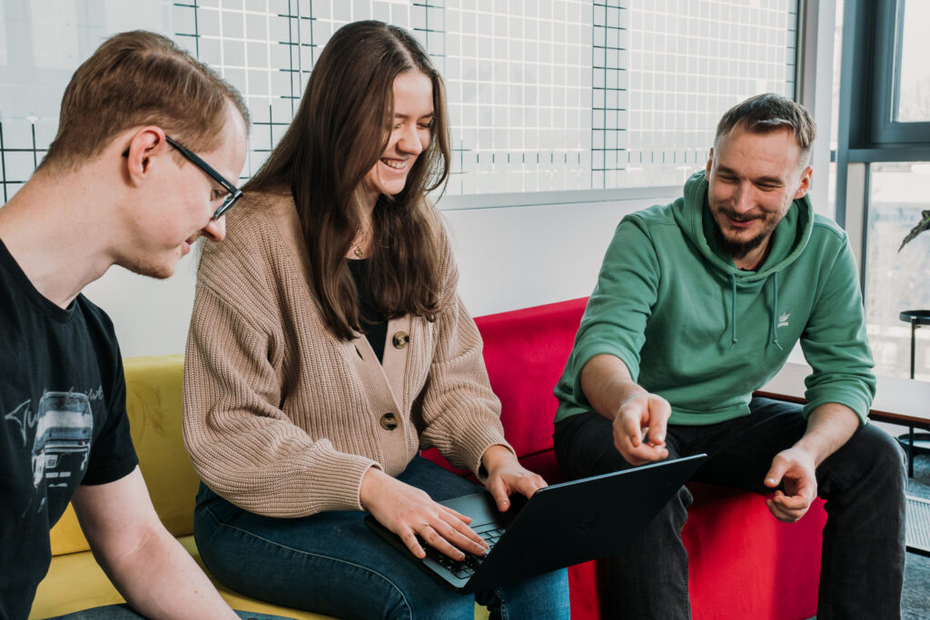 A group of Spyrosoft employees spend time together at the Spyrosoft office in Bialystok. The photo shows a woman and two men.