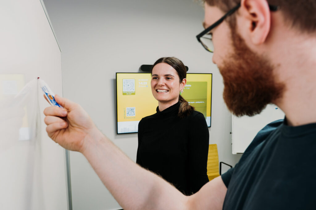Two Spyrosoft employees are in a conference room, mapping out project milestones on a whiteboard.