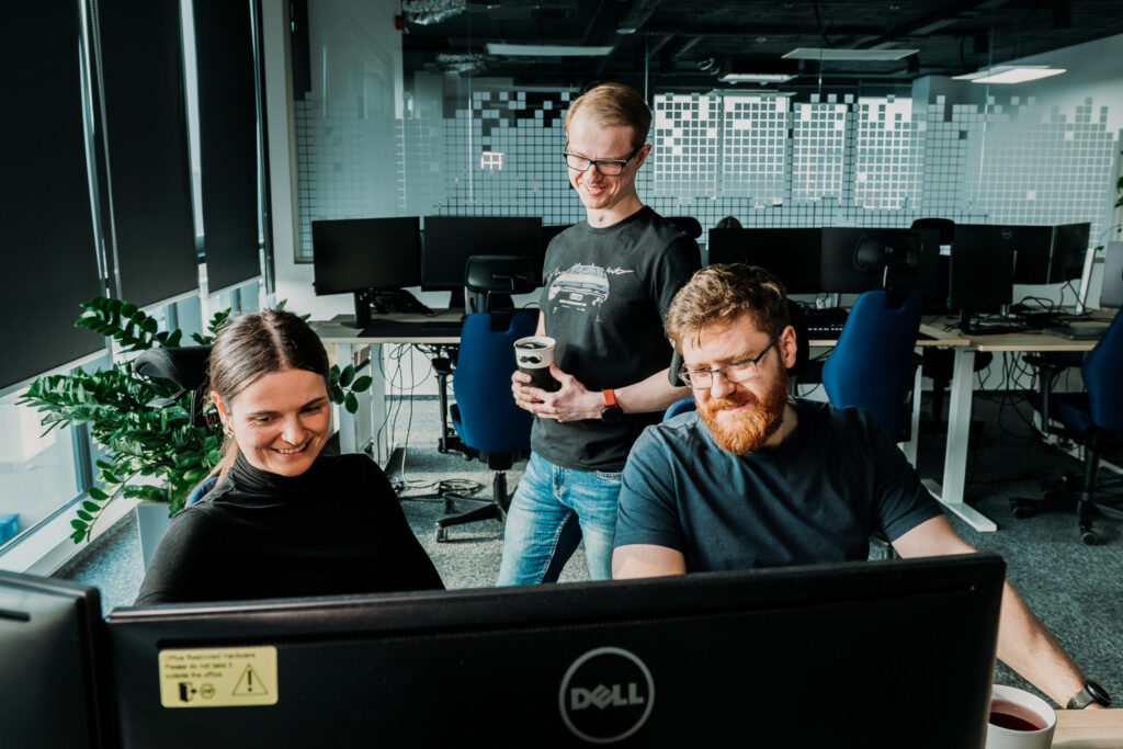 A group of Spyrosoft employees work together in front of a computer in an office in Bialystok.