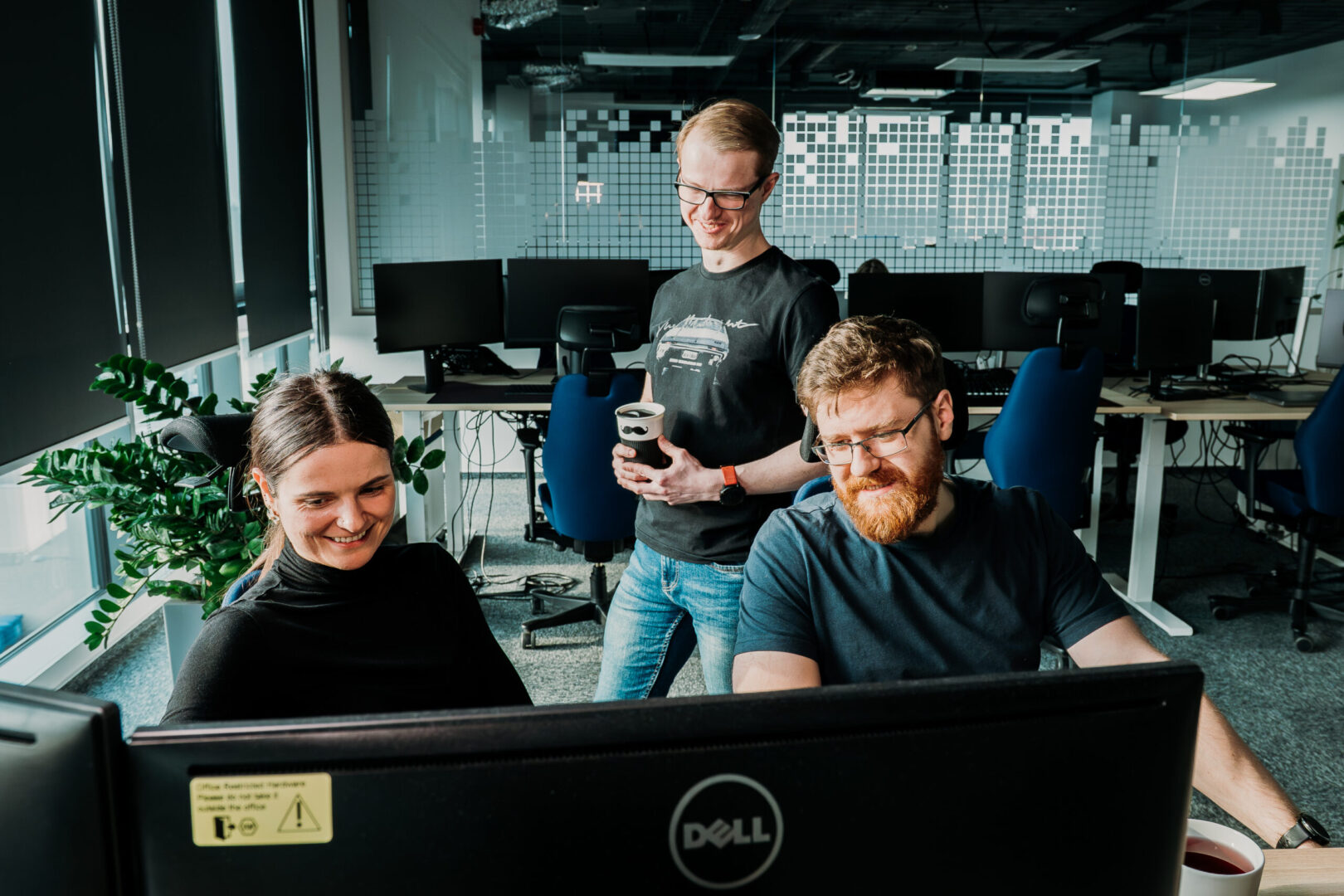 A group of Spyrosoft employees work together in front of a computer in an office in Bialystok.