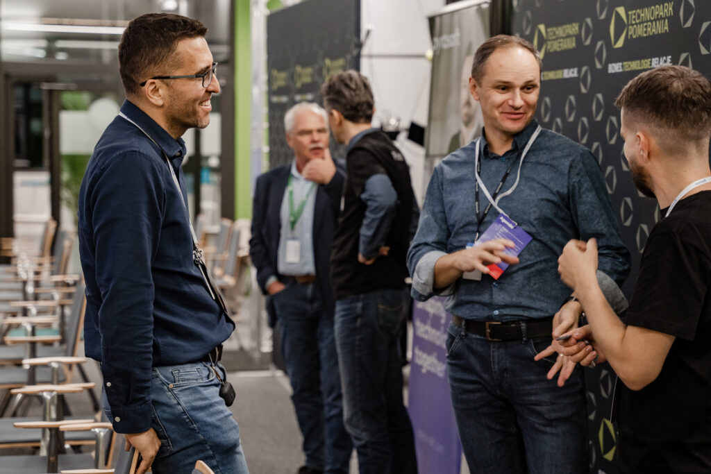 Three men, who are employees of Spyrosoft, talk to each other during an event organized by the company.