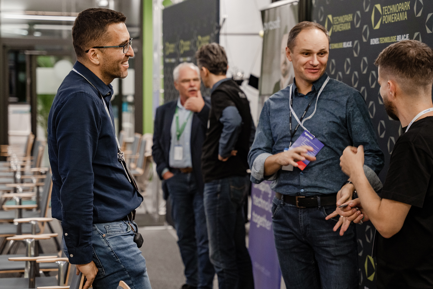 Three men, who are employees of Spyrosoft, talk to each other during an event organized by the company.